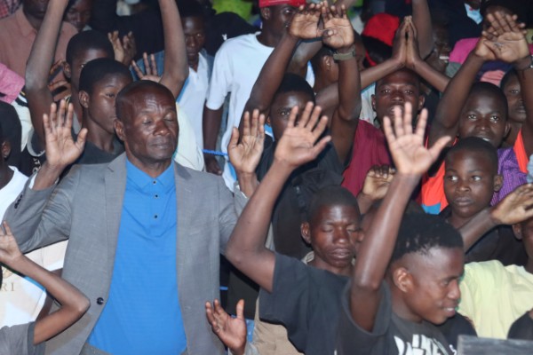 Village crusade in Mozambique — people praying with hands raised